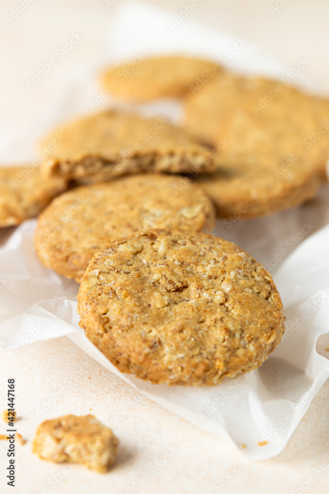 Healthy oatmeal or multigrain cookies with seeds and nuts on baking paper, light concrete background.