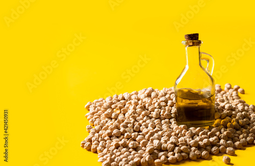 .Raw chickpea beans and chickpea cold-pressed oil in bottle on yellow background.