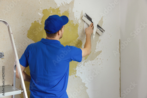 Fotografie worker removing old painted wallpaper from the wall