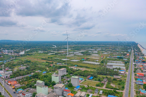 Aerial view of wind turbine with residential buildings in Nakhon Si Thammarat with sea skyline, Thailand. Urban town city in Asia. Architecture landscape background. photo