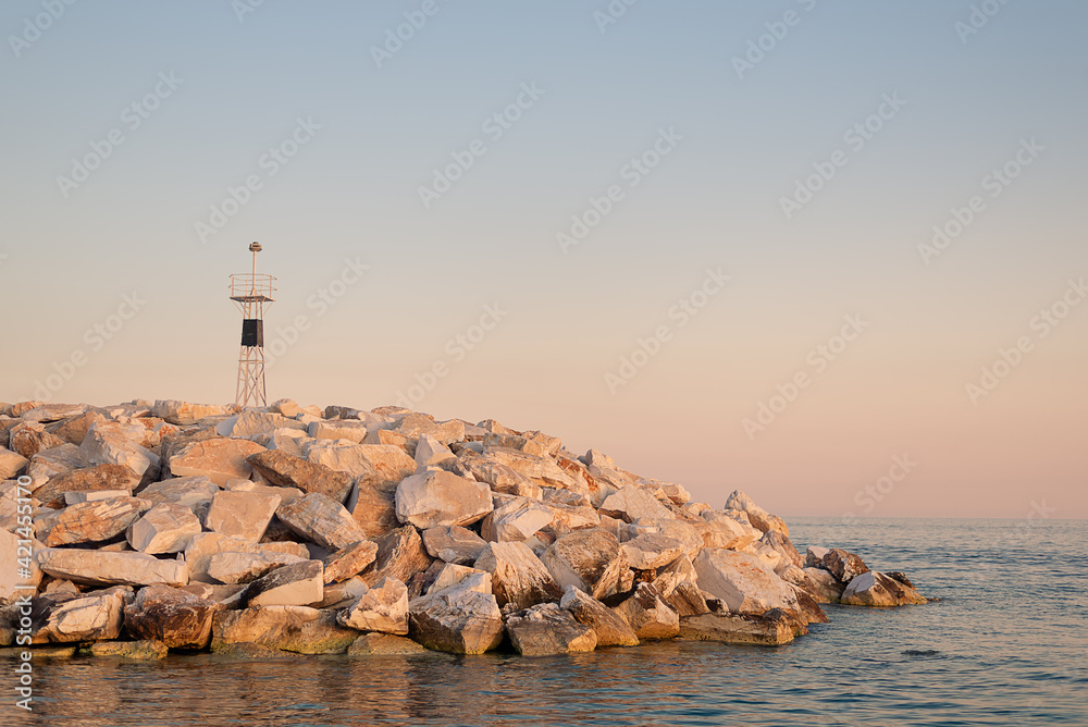 Lighthouse on wave breakers at sunset