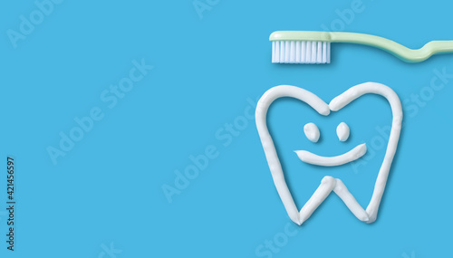 Tooth painted with toothpaste on blue background. Dental care concept.