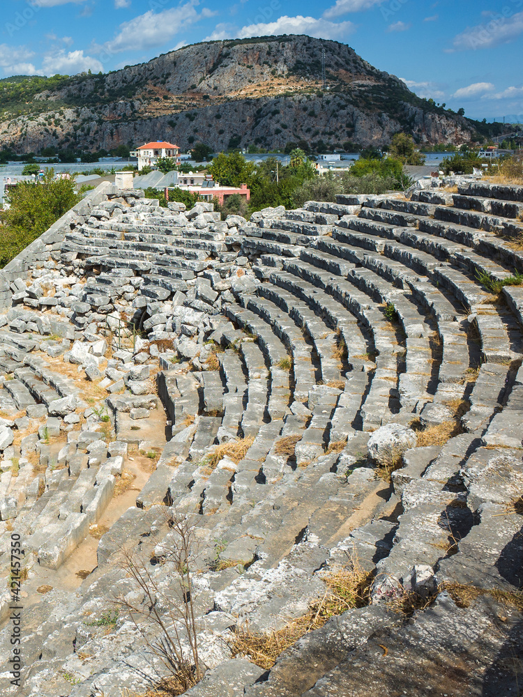 Rows of stone seats of ruins of Theatre in Letoon Ancient City in village Kumluova, Turkey. Sunny day, Greek culture ancient amphitheater architecture vertical photo