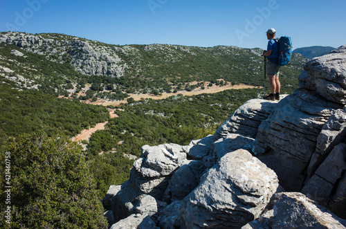 Hiking Lycian way. Man with backpack standing on big rock formation looking beautiful valley view on stretch between Saribelen and Gokceoren, Trekking in Turkey, outdoor activity photo