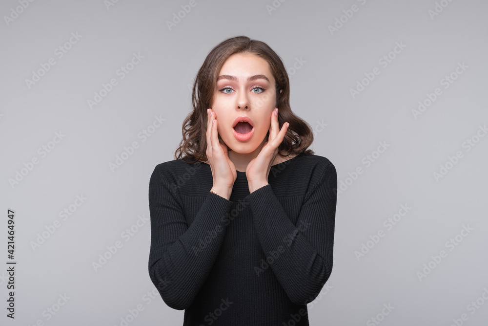 Portrait of shocked afraid woman looking with having wide open mouth gesturing palms, standing gray background Portrait of shocked afraid woman looking with having wide open mouth gesturing palms, standing gray background