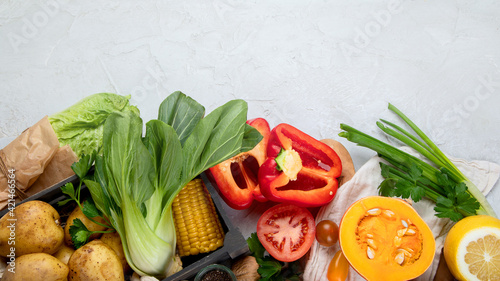 Selection of fresh raw vegetables, fruits and beans on light gray background.