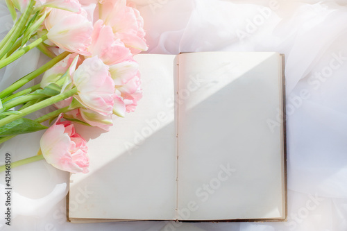  bouquet of tulips and an old book on the windowsill on the window #421468509