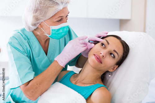 Young woman getting injection for facial correction procedure in esthetic clinic