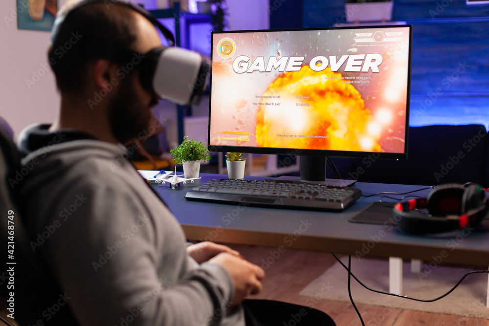 Over shoulder of focused cyber player wearing virtual reality headset during online championship. Game over for pro gamer using console for shooter gaming competition late at night in living room