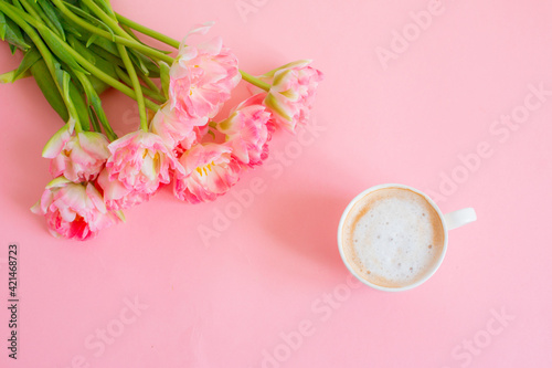 pink tulips and a cup of coffee on a pink background