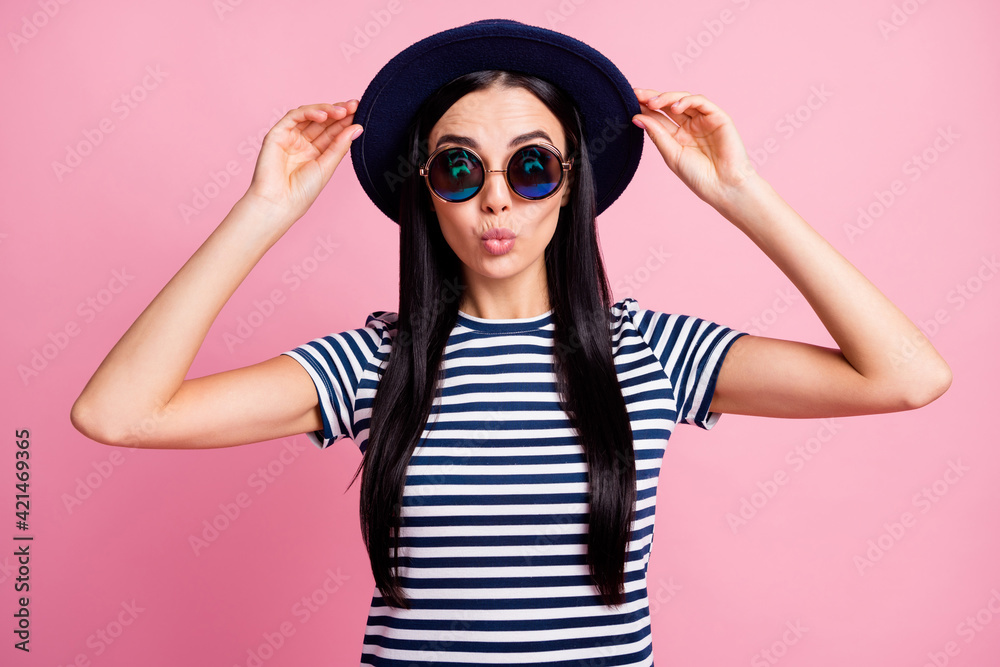 Photo portrait of amazed pouting woman holding hat with two hands isolated on pastel pink colored background Photo portrait of amazed pouting woman holding hat with two hands isolated on pastel pink colored background