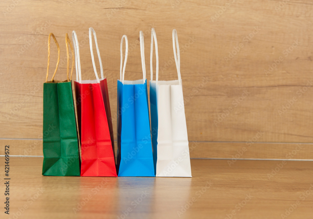 Colorful paper shopping bags on the floor against a wooden wall background
