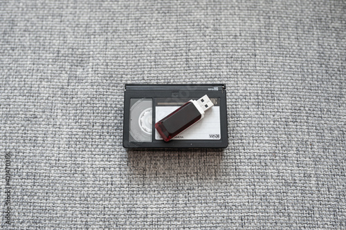 Old tape video cassette with usb flash disk on gray knitted background