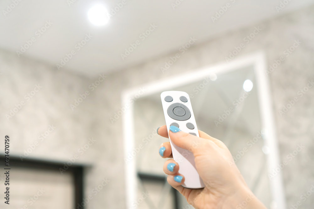 Smart home concept with female hand holding a remote control