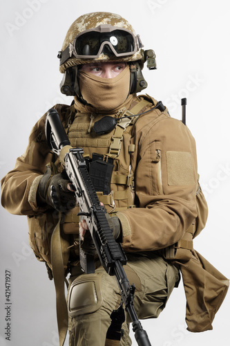 Male soldier in tactical equipment and uniform (coyote brown color) . Shot in studio on a white background