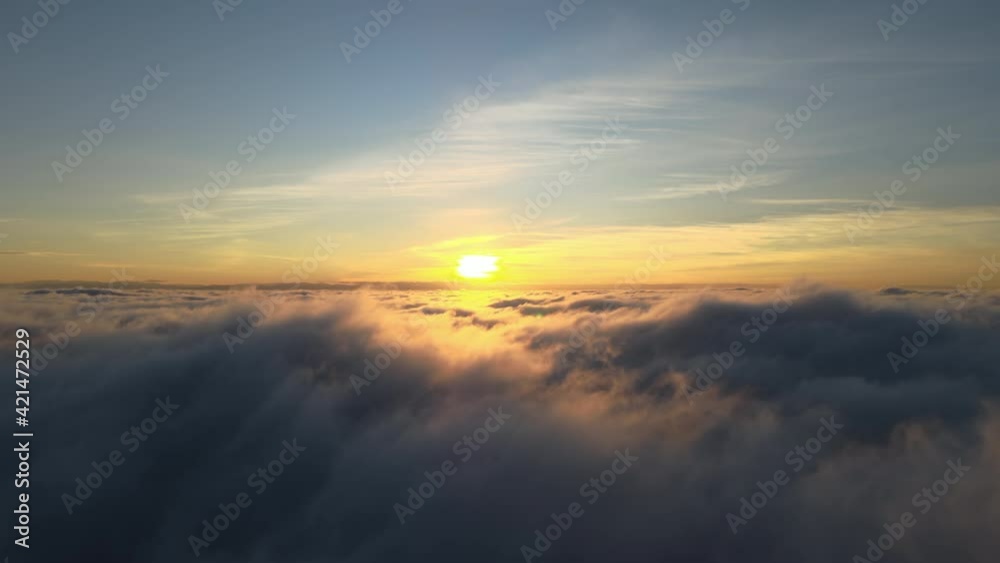 Aerial view of vibrant yellow sunrise over white dense clouds with blue sky overhead. Aerial view of vibrant yellow sunrise over white dense clouds with blue sky overhead.