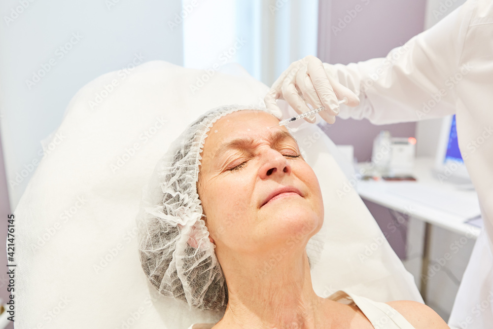 Doctor Injects Hyaluronic Acid Dermal Filler During A Facelift Stock Doctor injects hyaluronic acid dermal filler during a facelift stock