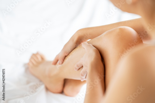Woman massaging legs on bed photo