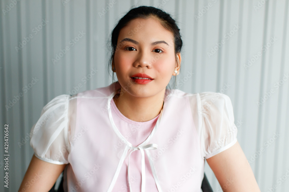 Close up portrait shot of Asian long black hair young female beautiful secretary smiling wearing white outer and pink inner sleeveless shirt sitting in front of blurred gray stripe wall background Close up portrait shot of Asian long black hair young female beautiful secretary smiling wearing white outer and pink inner sleeveless shirt sitting in front of blurred gray stripe wall background