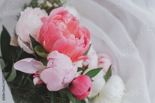 Beautiful stylish peonies bouquet on soft white fabric. Mothers day. Bridal morning. Space for text
