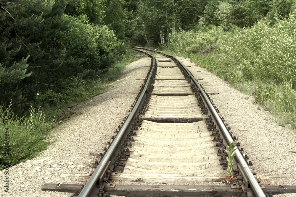 turn of the railway. Steel rails on concrete sleepers disappear from view, going deep into the forest thicket turn of the railway. Steel rails on concrete sleepers disappear from view, going deep into the forest thicket