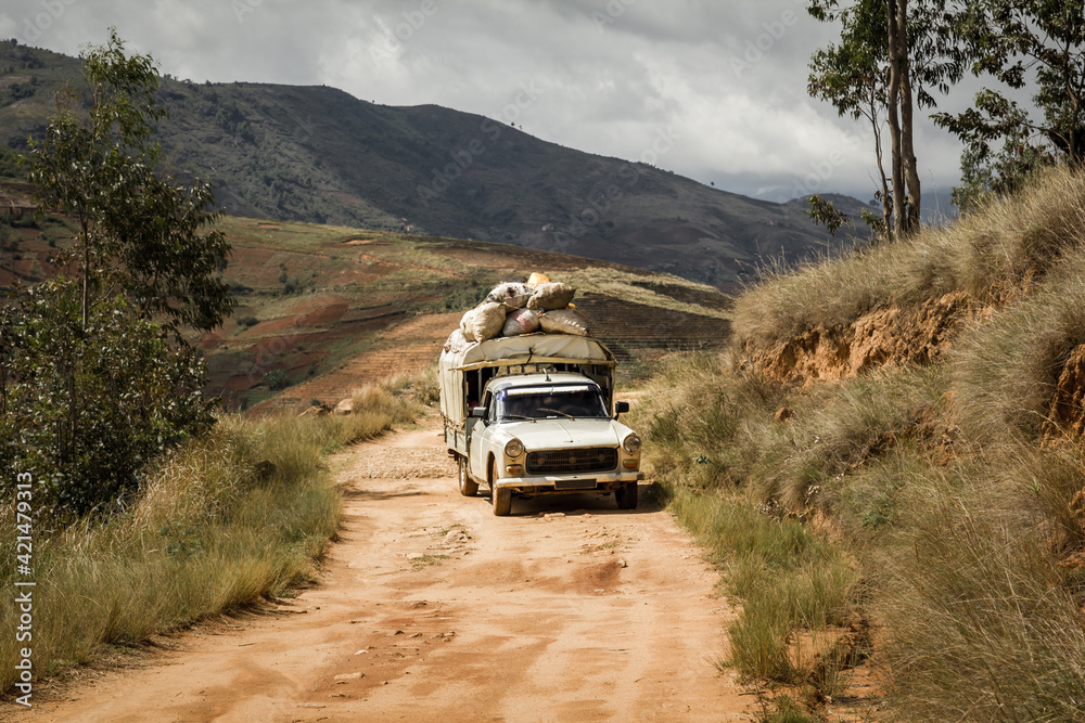 An old car fully loaded driving on the dusty road around Andringitra in Anbalavao District, Central Madagascar