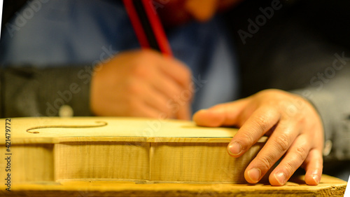 Fotografie Luthier violin maker working on wooden instrument with tools