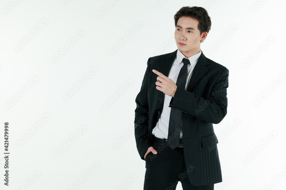 Portrait of self-confidence young and handsome Asian businessman in black suit standing in elegant pose and pointing finger, copy space studio shot isolated on white background Portrait of self-confidence young and handsome Asian businessman in black suit standing in elegant pose and pointing finger, copy space studio shot isolated on white background