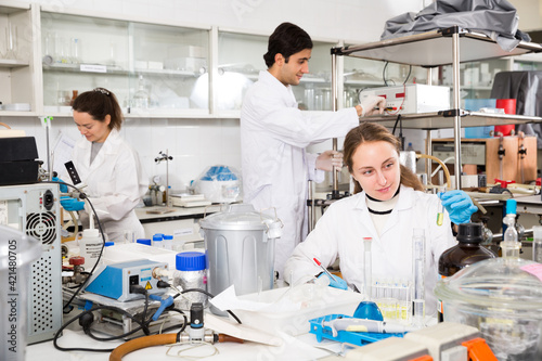 Young female scientist making research in chemical laboratory and taking notes in test chart..