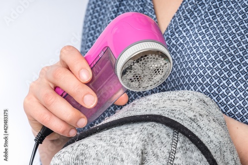 Fotografi Woman is removing lint with fabric shaver or fuzz remover