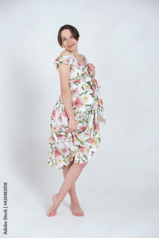Studio portrait of cheerful young pregnant woman in summer dress on white gray background, happy pregnancy concept Studio portrait of cheerful young pregnant woman in summer dress on white gray background, happy pregnancy concept