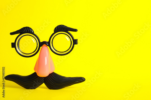 Funny face made with clown's accessories on yellow background, space for text