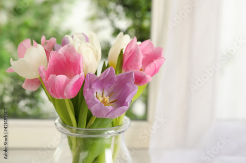 Beautiful fresh tulips near window indoors. Spring flowers