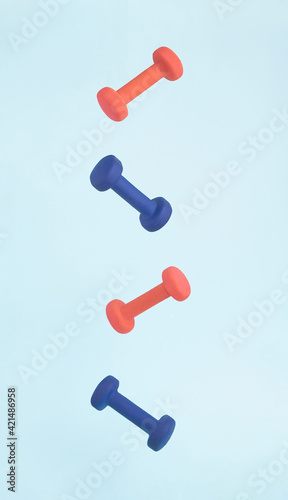 Pink and blue exercise dumbbell weights flying and floating in air in strong graphic line for art fitness concept.