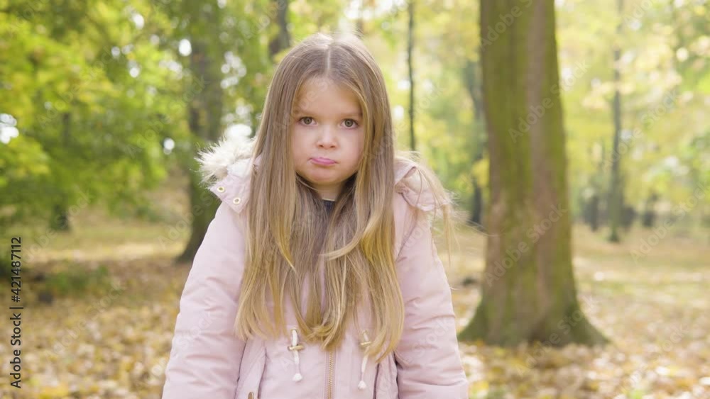 Cute little Caucasian girl is sulky and looks at the camera in a park Cute little Caucasian girl is sulky and looks at the camera in a park
