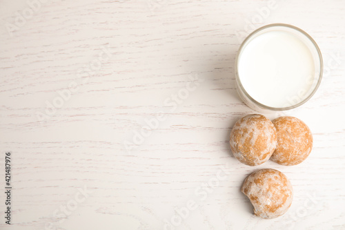 Tasty homemade gingerbread cookies and glass of milk on white wooden table, flat lay. Space for text