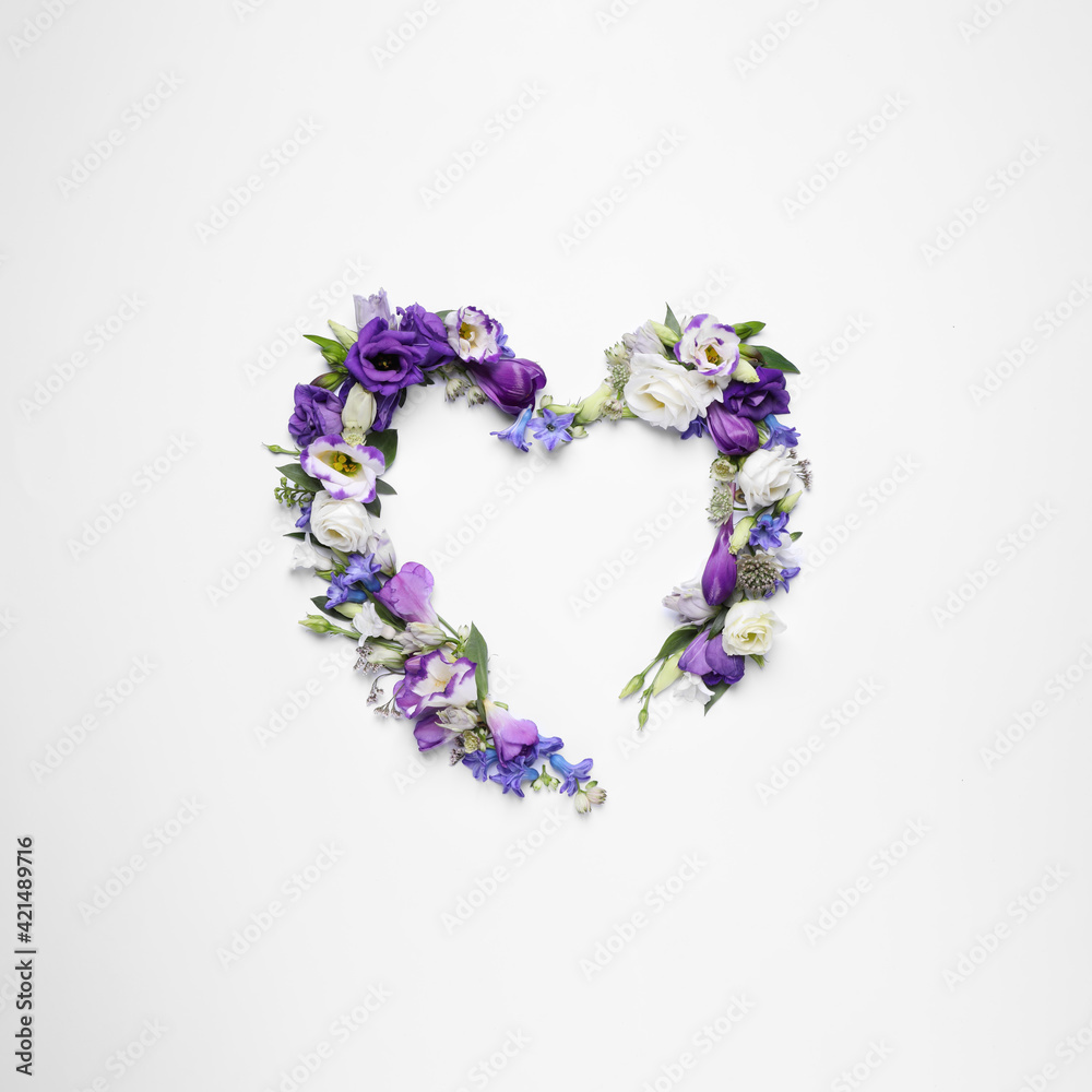 Beautiful heart made of different flowers on white background, top view