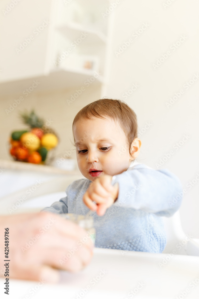 Funny little baby boy in the kitchen eating fruit puree from a bottle all dirty face.kitchen lifestyle, close up Funny little baby boy in the kitchen eating fruit puree from a bottle all dirty face.kitchen lifestyle, close up