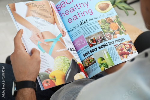 Man reading healthy food magazine indoors, closeup