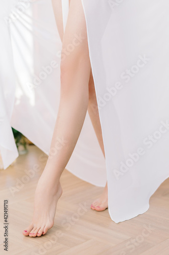 Running girl in a silk robe. Legs close-up, blurred background and selected focus. The bride's lifestyle. © NEZNAEV