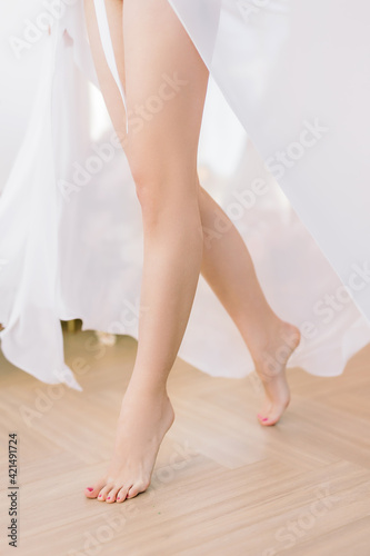 Running girl in a silk robe. Legs close-up, blurred background and selected focus. The bride's lifestyle.