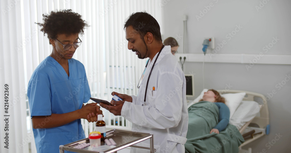 Multiethnic medical team with digital tablet examining female patient in hospital ward Multiethnic medical team with digital tablet examining female patient in hospital ward