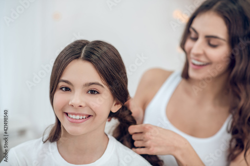 Mom braiding her happy daughters braids
