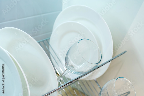 White plates and a wine glass lie on a metal dryer. Close-up. selective focus