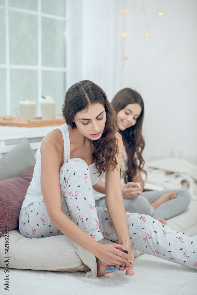 Woman painting toenails girl sitting behind Woman painting toenails girl sitting behind