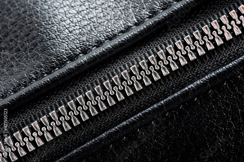 Black leather ladies bag with metal zippers, shot on a white background.