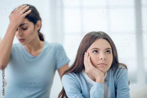 Stubborn teen daughter and upset mom behind photo