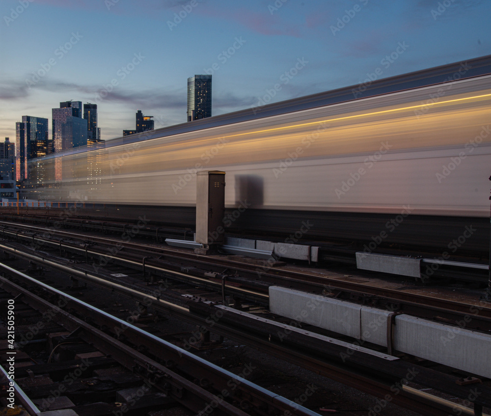 Fototapeta premium Moving train on city skyline background, with long exposure trail perspective 