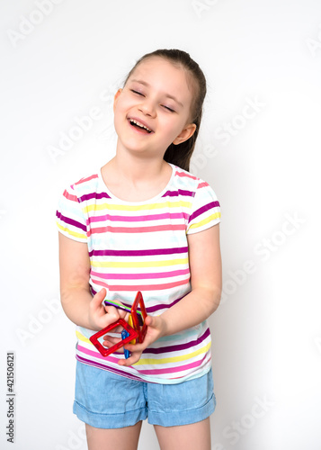 Kid plays with a magnetic constructor toy. A little child girl is playing with colorful blocks. Close up. Girl playing intellectual toys. Children's magnetic designer for development of motor skills.