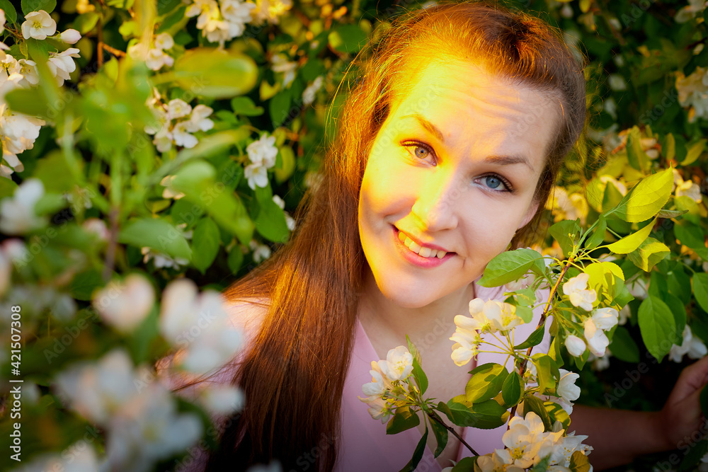 Fototapeta premium Beautiful woman with long hair walking in the park with blooming apple trees